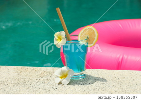 A colorful drink with flowers sits by the pool 138555307
