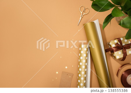 Gift wrapping materials. Rolls of wrapping paper, ribbon, gift. Brown background, space for your text. Preparing for the holidays Gift wrapping materials. Rolls of wrapping paper, ribbon, gift. Brown background, space for your text. Preparing for the holidays 138555386