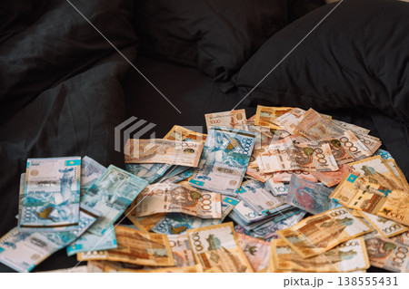 Pile of Kazakhstani tenge banknotes on black sofa, cash savings and wealth concept 138555431