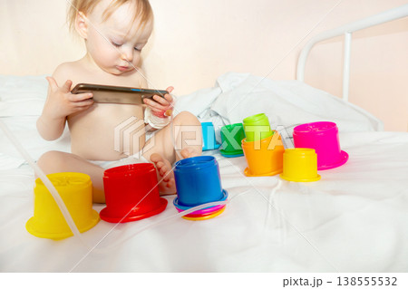 child in hospital lying in bed with mobile phone smiling 138555532