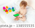 child in hospital lying in bed with mobile phone smiling 138555535