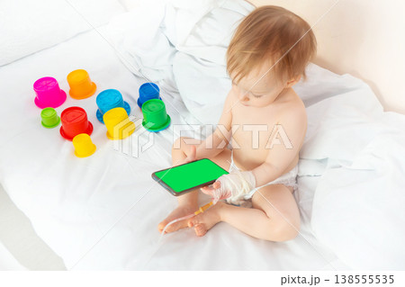 child in hospital lying in bed with mobile phone smiling 138555535