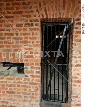 A close-up of a heavy iron-barred door and weathered brickwork of a solitary cell at the historic Cellular Jail in Port Blair. 138555982