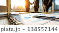 Photo of business meeting with financial charts and handshake in the background, city view, sunlight. 138557144