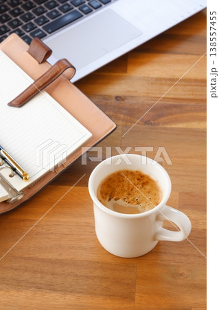 淹れたての美味しいコーヒーを飲みながら、ノートパソコンとシステム手帳でデスクワークをしているイメージ 淹れたての美味しいコーヒーを飲みながら、ノートパソコンとシステム手帳でデスクワークをしているイメージ 138557455