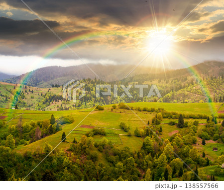 rural mountain landscape during spring at sunset. wonderful countryside scenery on a cold weather in evening light. cloudy sky above rolling hills in may. timeless nostalgia book cover with rainbow 138557566