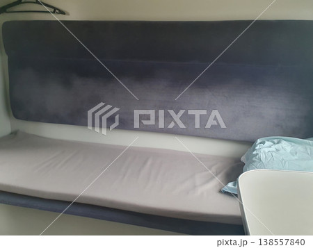 Interior of a modern train sleeping car. Comfortable passenger seat with soft upholstery, clothes hangers and clean bed Interior of a modern train sleeping car. Comfortable passenger seat with soft upholstery, clothes hangers and clean bed 138557840