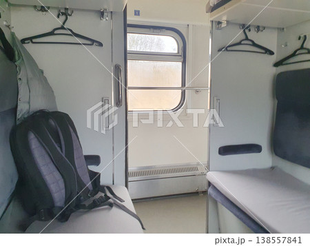 Interior of a modern passenger car with a backpack on the seat and a window. Cozy compartment for travel, clean bedding 138557841