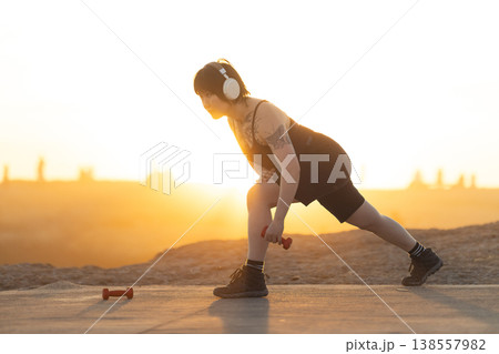 Woman training outdoors at sunset performing lunges Woman training outdoors at sunset performing lunges 138557982