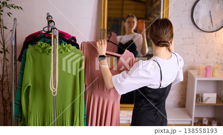 Woman choosing clothes in front of mirror trying outfit at home. Woman choosing clothes in front of mirror trying outfit at home. 138558193