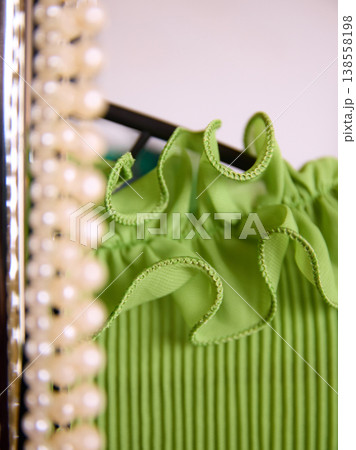 Close up of green dress fabric with texture and pearl accessories. 138558198