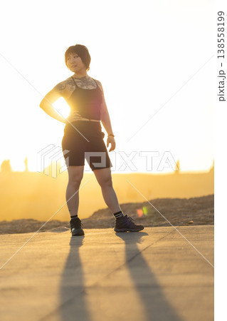 Confident young woman posing during golden hour sunset 138558199