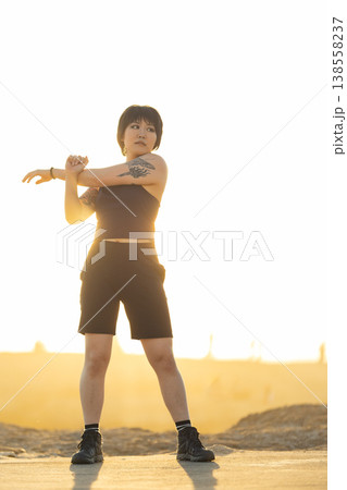 Woman stretching arm starting outdoor workout at sunrise 138558237