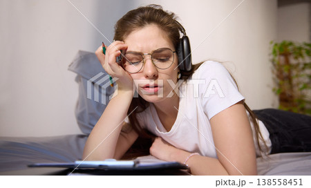 Young woman feeling tired while studying online with headphones at home. Young woman feeling tired while studying online with headphones at home. 138558451