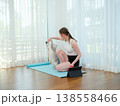 Young woman resting after workout at home with her cat. Concept of fitness, pet companionship, and healthy lifestyle. Female relaxing on yoga mat and playing with domestic animal. 138558466