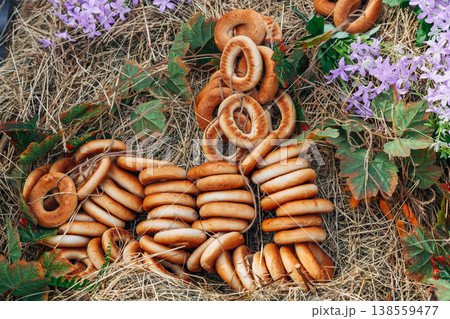 Still life: a multitude of bagels on a rope decorated with purple flowers. On hay. 138559477