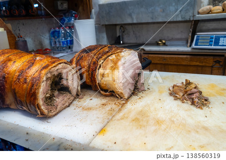 Two large cuts of roasted pork, one sliced, sit on a cutting board in a butcher shop with a scale in the background Two large cuts of roasted pork, one sliced, sit on a cutting board in a butcher shop with a scale in the background 138560319