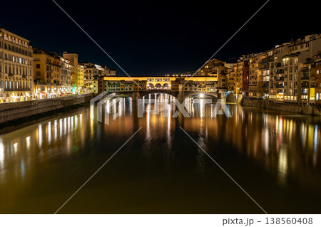 The historic Ponte Vecchio bridge in Florence, Italy, glows with warm lights reflecting on the Arno River at night The historic Ponte Vecchio bridge in Florence, Italy, glows with warm lights reflecting on the Arno River at night 138560408