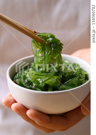 Fresh Japanese seaweed salad (Chuka Wakame) being picked up with chopsticks from a bowl in hand Fresh Japanese seaweed salad (Chuka Wakame) being picked up with chopsticks from a bowl in hand 138560782