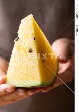 Close-up of woman's hands holding sliced yellow watermelon, healthy tropical fruit for summer season Close-up of woman's hands holding sliced yellow watermelon, healthy tropical fruit for summer season 138560808
