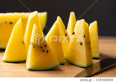 Sliced yellow watermelon and knife on cutting wooden board, healthy tropical fruit for summer season Sliced yellow watermelon and knife on cutting wooden board, healthy tropical fruit for summer season 138560809