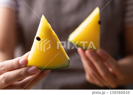 Close-up of woman's hands holding sliced yellow watermelon and eat Close-up of woman's hands holding sliced yellow watermelon and eat 138560810