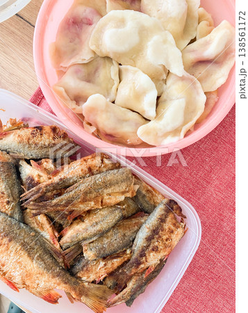 A plate holds fried carp next to a bowl and dumplings with potatoes. This healthy breakfast is prepared for a meal. It features fish and potatoes on a red cloth 138561172