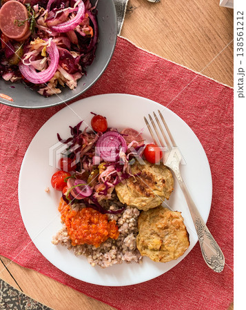A healthy breakfast plate includes green buckwheat, chicken cutlets, zucchini caviar, and a side salad with radish and tomatoes. Fresh ingredients are showcased on a simple table setting A healthy breakfast plate includes green buckwheat, chicken cutlets, zucchini caviar, and a side salad with radish and tomatoes. Fresh ingredients are showcased on a simple table setting 138561212