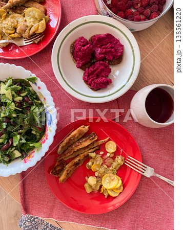 A breakfast spread includes grilled smelt fish with baked vegetables, fresh salad, beetroot hummus on gluten-free bread, and a drink. The meal is colorful and nutritious A breakfast spread includes grilled smelt fish with baked vegetables, fresh salad, beetroot hummus on gluten-free bread, and a drink. The meal is colorful and nutritious 138561220