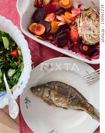 Baked sea bass is served with a salad made of carrots, broccoli, radishes, and greens. Baked pears complete the meal. This meal is gluten-free and healthy 138561234