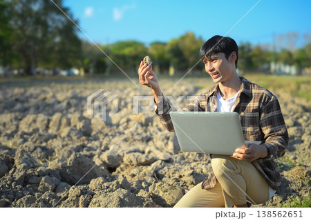 Farmer analyzing soil sample with laptop in dry field Farmer analyzing soil sample with laptop in dry field 138562651