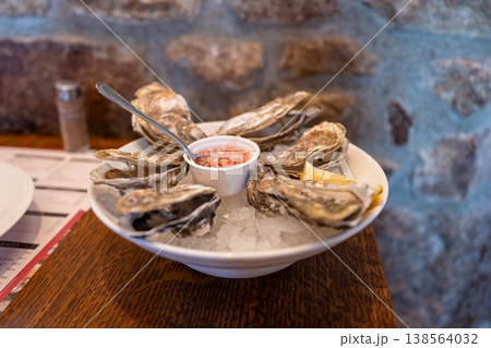 Fresh oysters on ice with lemon and sauce served on plate gourmet seafood appetizer restaurant dining concept Fresh oysters on ice with lemon and sauce served on plate gourmet seafood appetizer restaurant dining concept 138564032