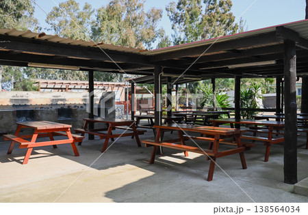 Wooden picnic tables under covered shelter in campsite park outdoor dining area travel and leisure concept 138564034