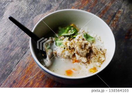 Top view of fresh Minced pork porridge in white bowl on wooden table is traditional breakfast Thai food Top view of fresh Minced pork porridge in white bowl on wooden table is traditional breakfast Thai food 138564103