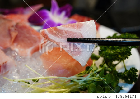close-up photo of a piece of fresh tuna sashimi picked up with chopsticks. close-up photo of a piece of fresh tuna sashimi picked up with chopsticks. 138564171