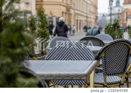 Empty outdoor cafe tables and chairs with a distinctive pattern await customers on a quiet city street, reflecting urban leisure and hospitality 138564599
