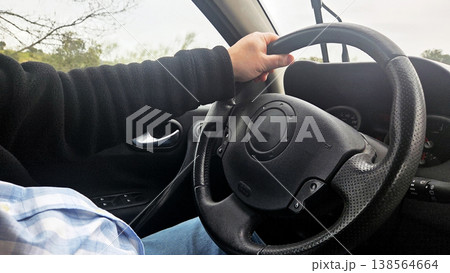Driver hands on steering wheel inside car interior for safe driving tutorial and website banner background Driver hands on steering wheel inside car interior for safe driving tutorial and website banner background 138564664