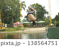 Young man doing a backflip into the river from a pier on a summer beach 138564751