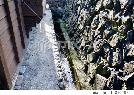 石垣に沿う水路・古い石積み造成と苔むした岩肌の風情 138564870