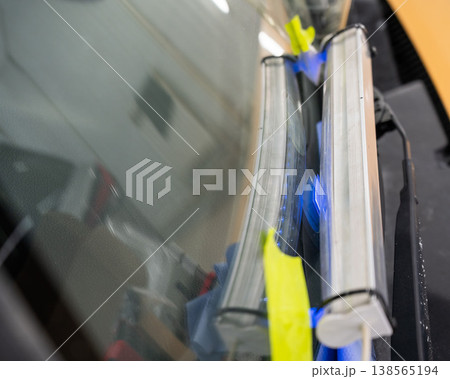 Windshield chip repair. A UV lamp dries the resin in the crack. Windshield chip repair. A UV lamp dries the resin in the crack. 138565194