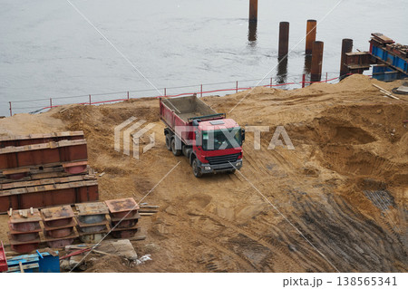 Large sand pile being unloaded by trucks at construction zone Large sand pile being unloaded by trucks at construction zone 138565341