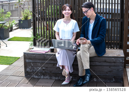 リモートワーク中に屋外でコーヒーを飲みながら会話を楽しむ若い男女 138565528