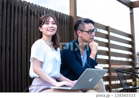 リモートワーク中に屋外でコーヒーを飲みながら会話を楽しむ若い男女 138565533