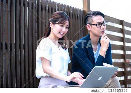 リモートワーク中に屋外でコーヒーを飲みながら会話を楽しむ若い男女 138565535