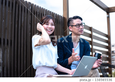 リモートワーク中に屋外でコーヒーを飲みながら会話を楽しむ若い男女 138565536