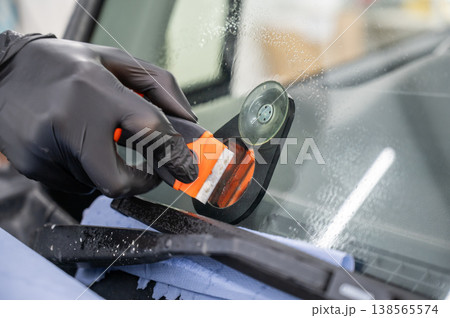 Repairing a chip on a car windshield.  138565574