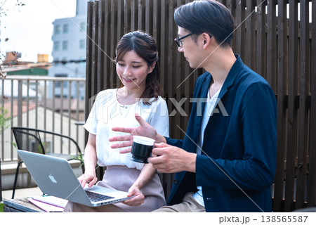 リモートワーク中に屋外でコーヒーを飲みながら会話を楽しむ若い男女 138565587