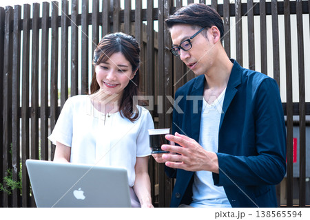 リモートワーク中に屋外でコーヒーを飲みながら会話を楽しむ若い男女 138565594