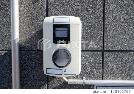 Electric vehicle charging socket on wall with contactless payment terminal modern EV charging station concept 138565767