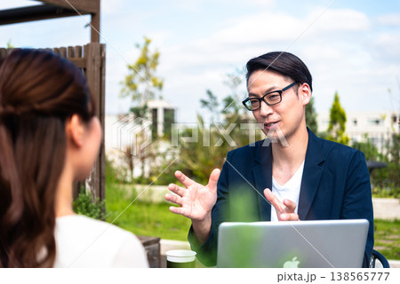 テラス席でノートパソコンを囲み打ち合わせをするビジネス男女 138565777